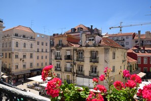 Un edificio histórico con varios balcones y techo de tejas rojas, rodeado de otros edificios y una grúa de construcción al fondo.