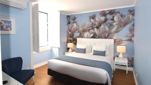 Quarto com cama, duas mesinhas de cabeceira, uma cadeira e ar-condicionado fixado na parede.