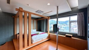 A modern bedroom with a wooden bed frame, a large window with a view of buildings, and a ceiling fan. - LiChiuan Hotel Spring Hotel (Tainan)