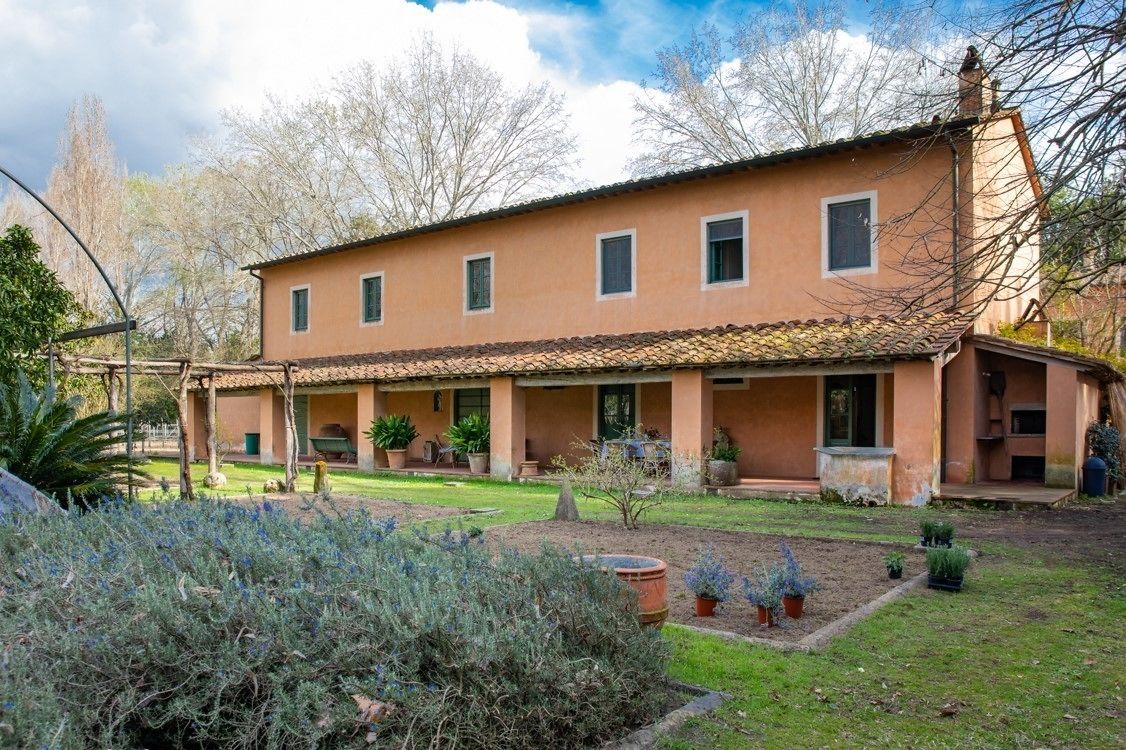 A two-story building with a tiled roof and a covered patio area.