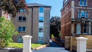 A pathway leading to a residential building with a brick facade and multiple windows. - Alison Court (Bristol)