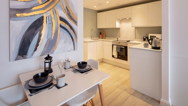 A modern kitchen with white cabinets, a built-in oven, and a coffee maker. - Alison Court (Bristol)
