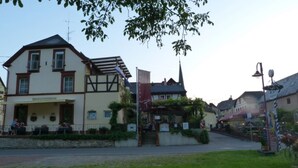 A building with a traditional architectural style, featuring a gabled roof and a balcony. There are flags and signs indicating a welcoming atmosphere. - Moselperle (Traben-Trarbach)