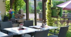 An outdoor patio with tables and chairs, a fountain, and greenery. - Moselperle (Traben-Trarbach)