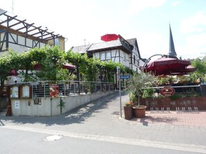 A restaurant with outdoor seating, a sign indicating 'Uferstraße', and a church spire in the background. - Moselperle (Traben-Trarbach)