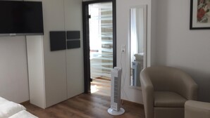 A modern bedroom with a bed, a wardrobe, a TV, a standing fan, and a chair. - Moselperle (Traben-Trarbach)