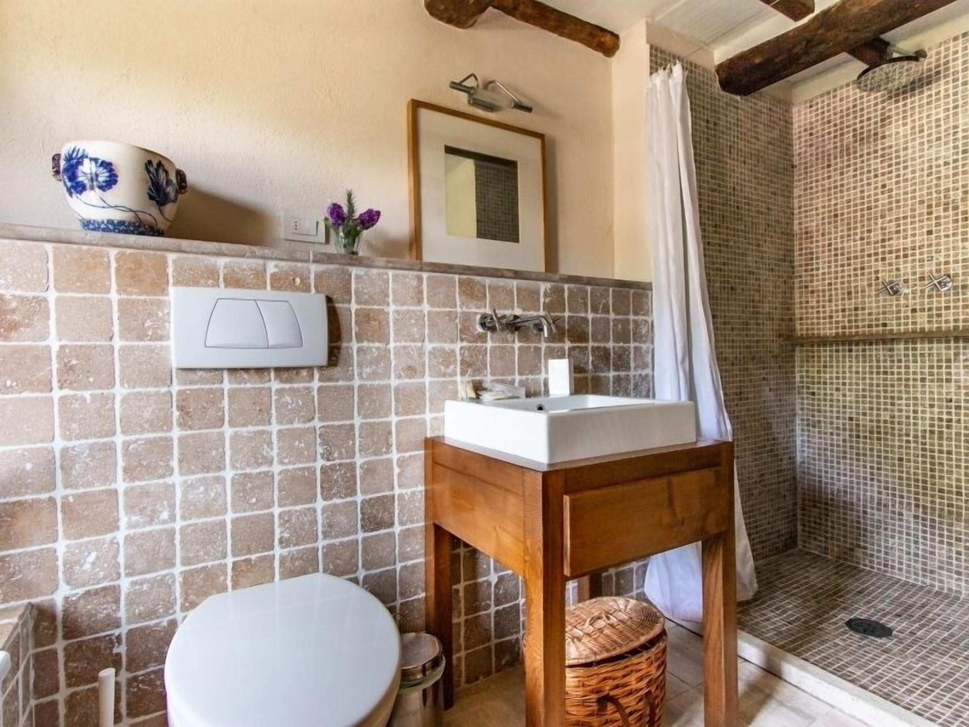 Une salle de bain avec une douche carrelée, un lavabo et des toilettes.