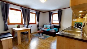 Un espace de vie compact comprenant un coin repas, un canapé et une kitchenette.