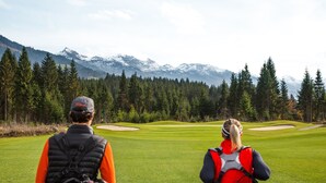 Un parcours de golf avec une chaîne de montagnes en arrière-plan.