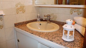 A bathroom with a granite countertop sink, a mirror above it, and a white cabinet below.