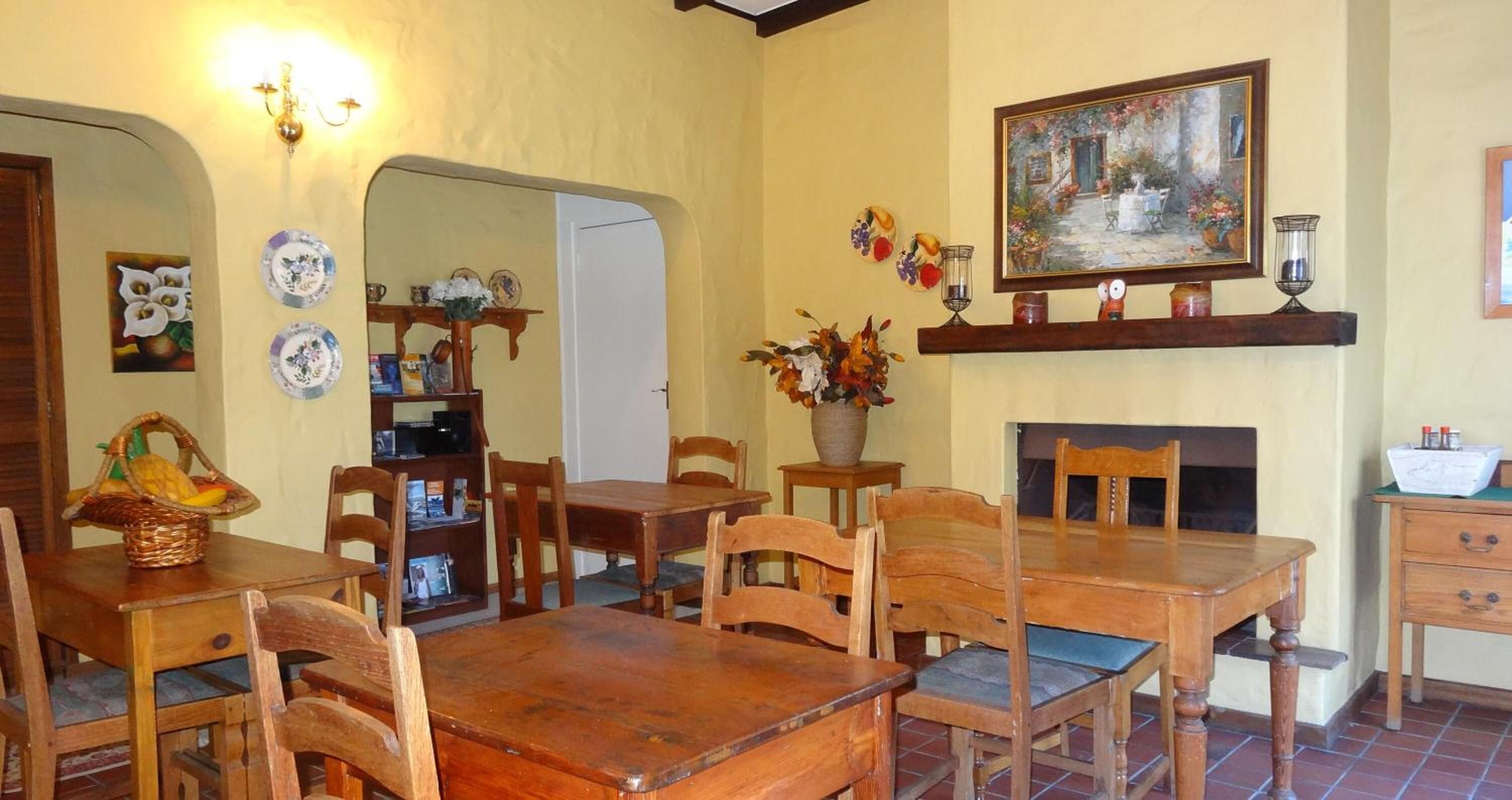 Ein Essbereich mit Holztischen und -stühlen, einem Kamin und verschiedenen dekorativen Gegenständen an den Wänden.