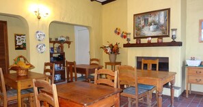 A dining area with wooden tables and chairs, a fireplace, and various decorative items on the walls. - Be My Guest Lodge (Cape Town)