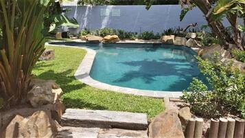 A swimming pool surrounded by rocks and greenery.