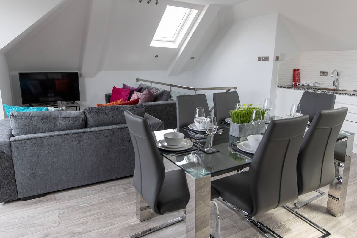 Un appartement moderne de style « loft » comprenant un coin repas, un canapé et un téléviseur.