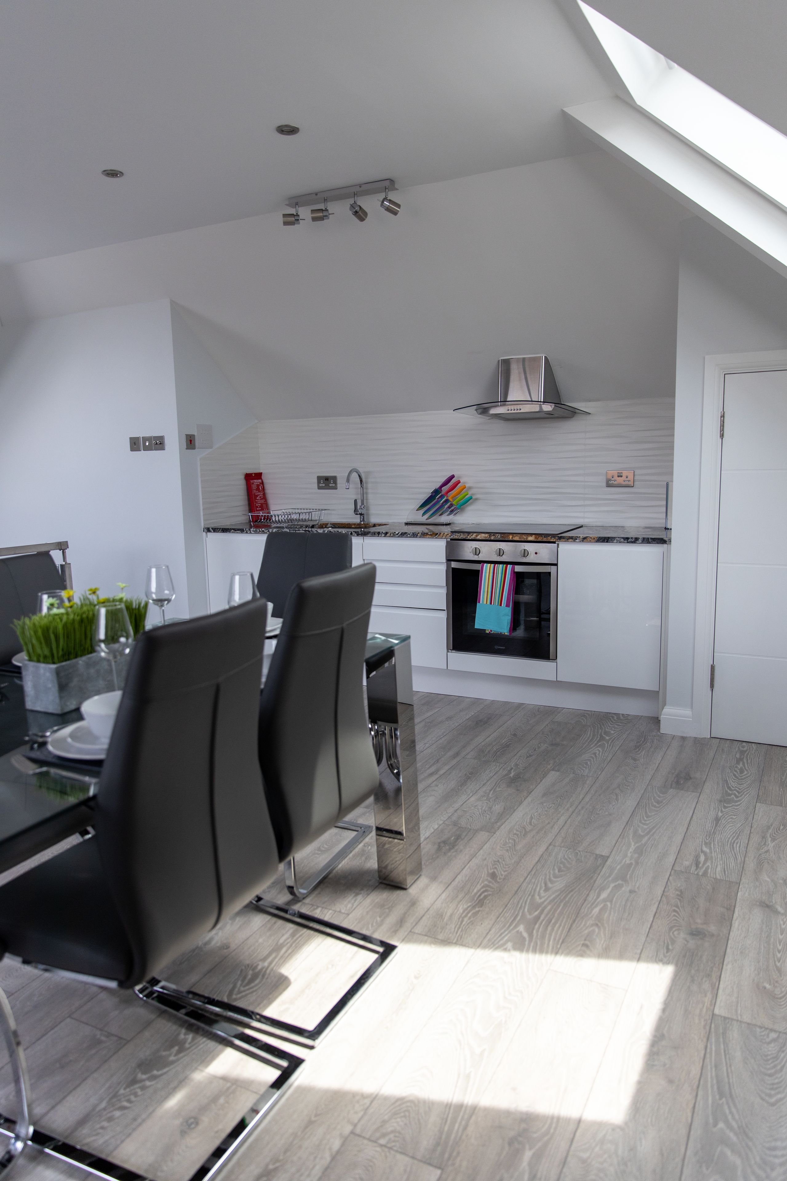 A modern kitchen with white cabinetry, a built-in oven, and a skylight.