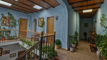 A multi-level interior with wooden beams, potted plants, and a staircase.