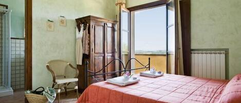 A bedroom with a bed, a wooden wardrobe, a chair, and a window with a view.