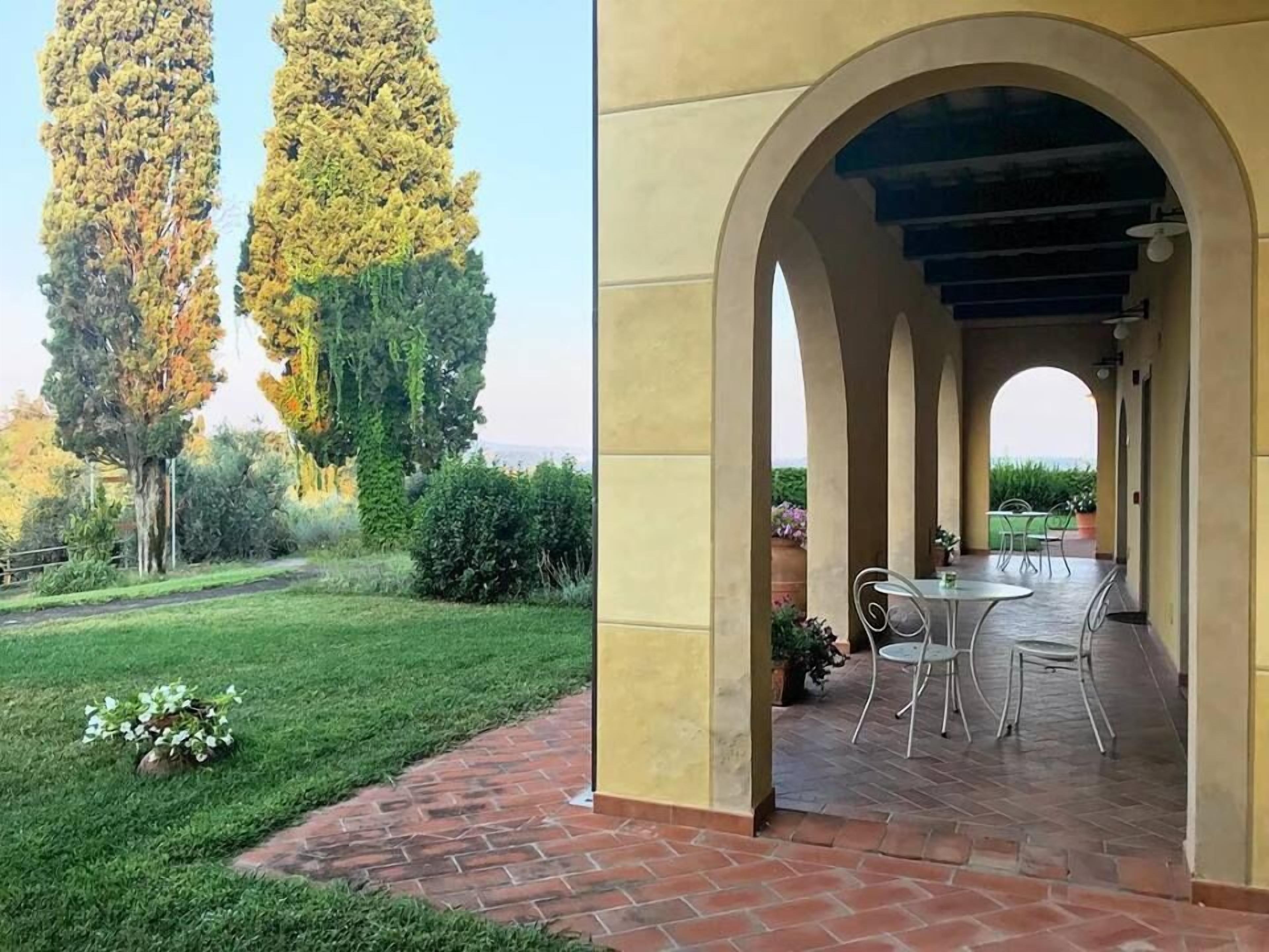 A patio with a brick floor and a covered seating area with metal chairs and a table.