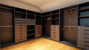 A walk-in closet with multiple shelves and drawers, wooden flooring, and hanging space.