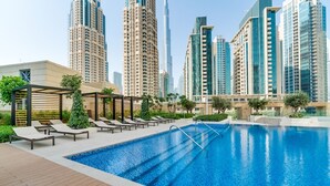 A swimming pool with lounge chairs and a pergola, surrounded by high-rise buildings. - Vida Downtown Residences (Dubai)