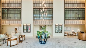 A spacious lobby with a central round table adorned with potted plants, flanked by seating areas and framed artwork on the walls. - Vida Downtown Residences (Dubai)