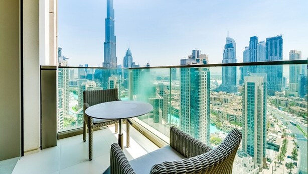 A balcony with a glass railing overlooking a cityscape with high-rise buildings. - Vida Downtown Residences (Dubai)