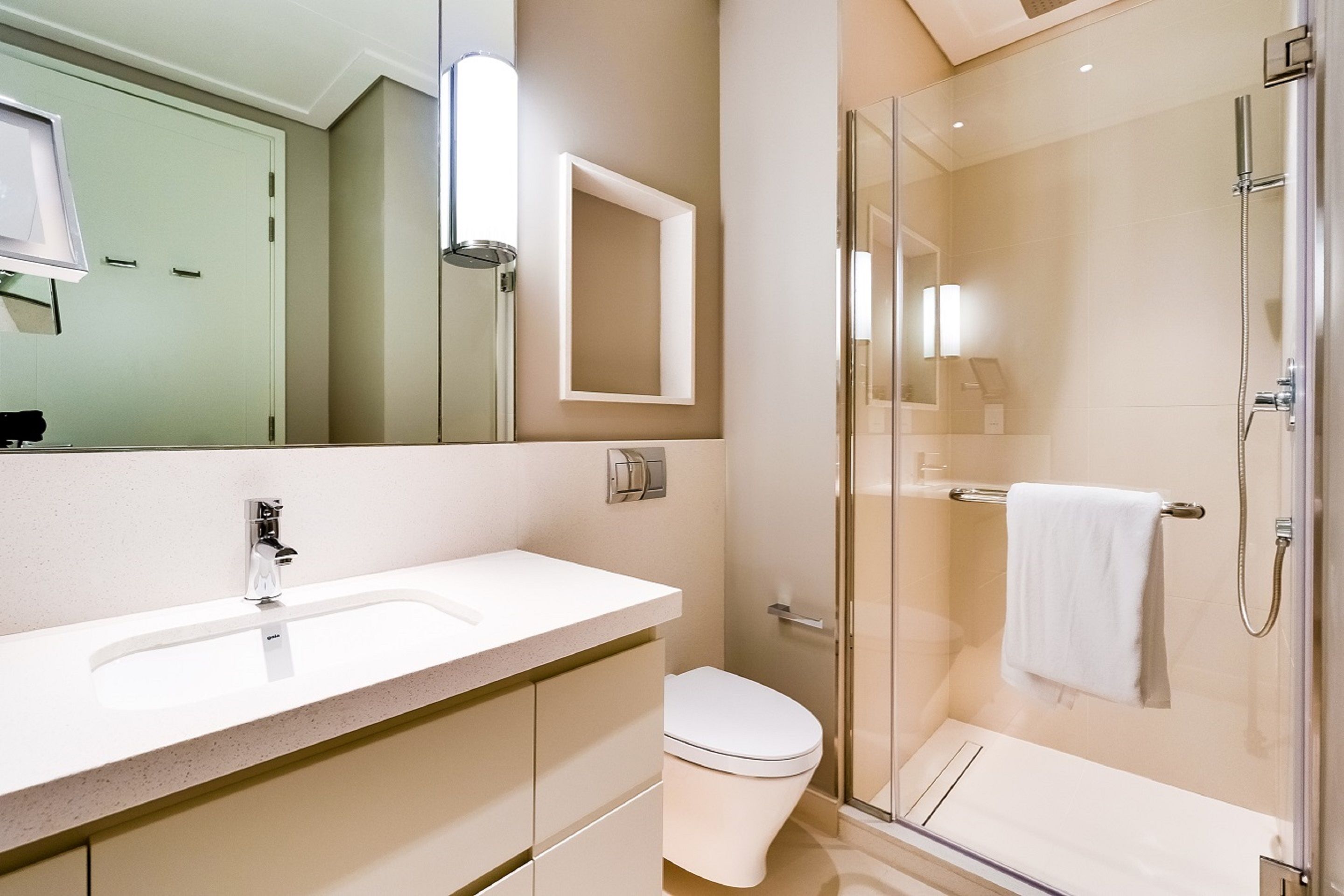 A modern bathroom with a glass shower enclosure, a white sink, and a toilet.