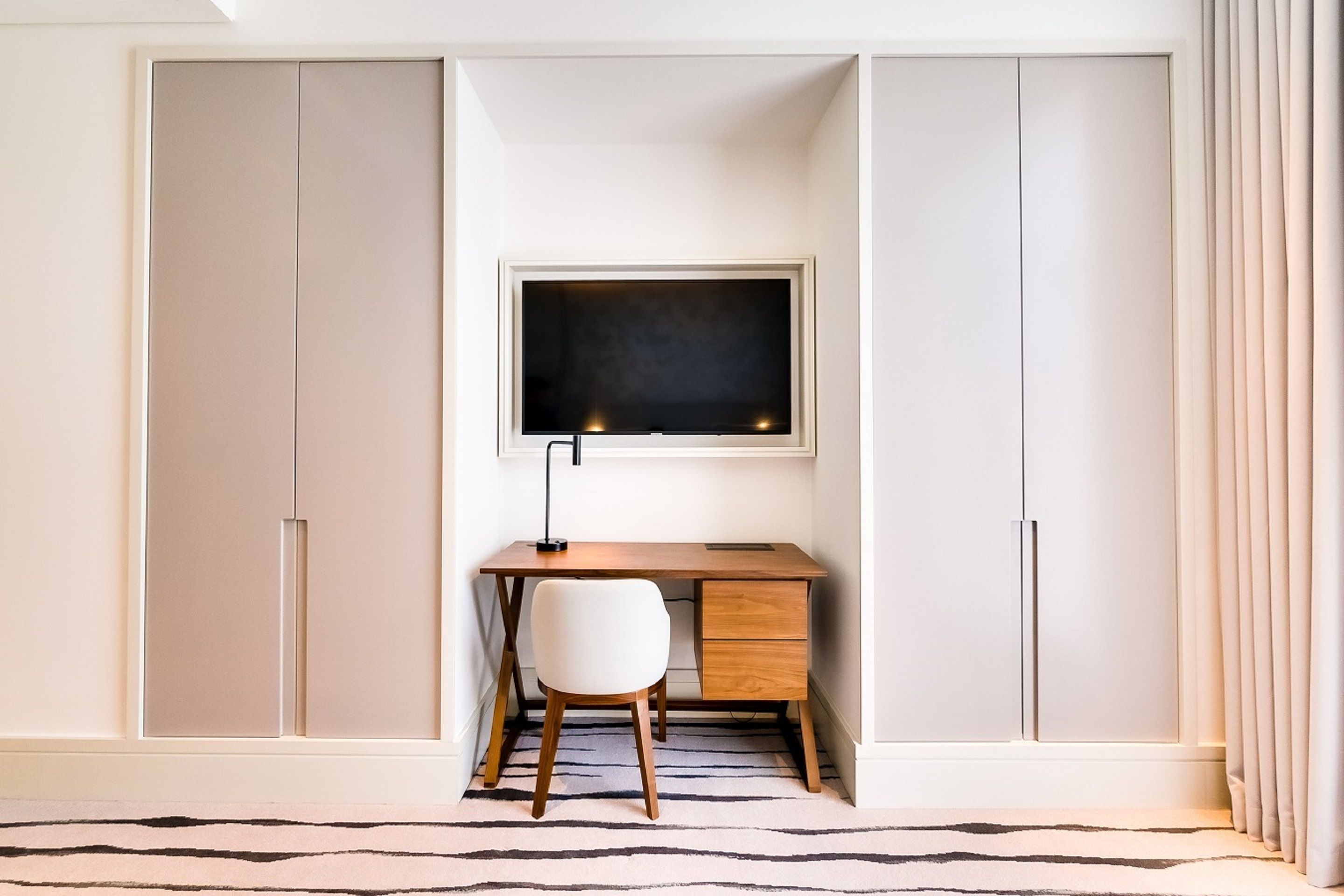 A study room with a desk, chair, and a television.
