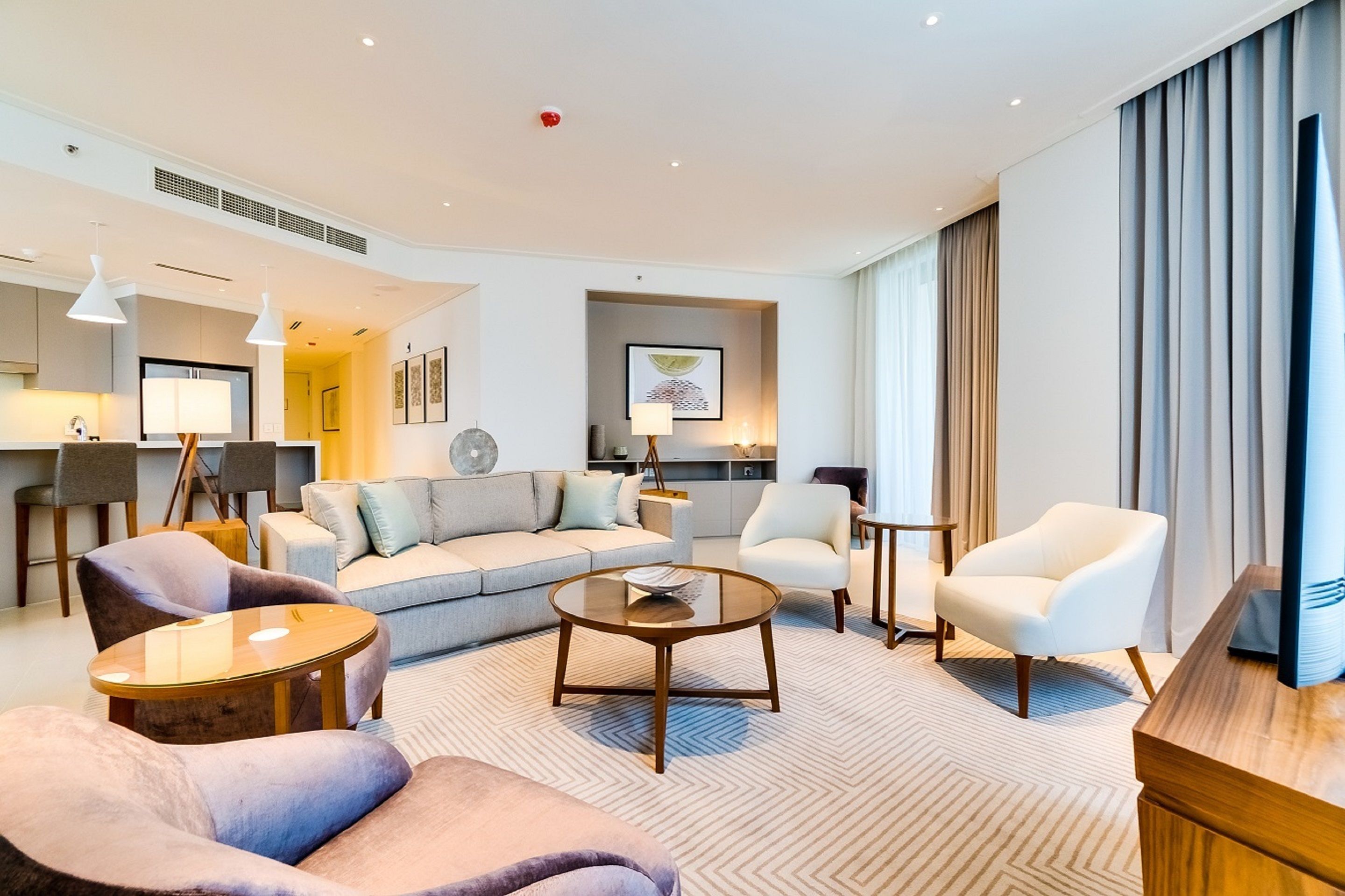 A modern living room with a sofa, armchairs, a coffee table, and a dining area.
