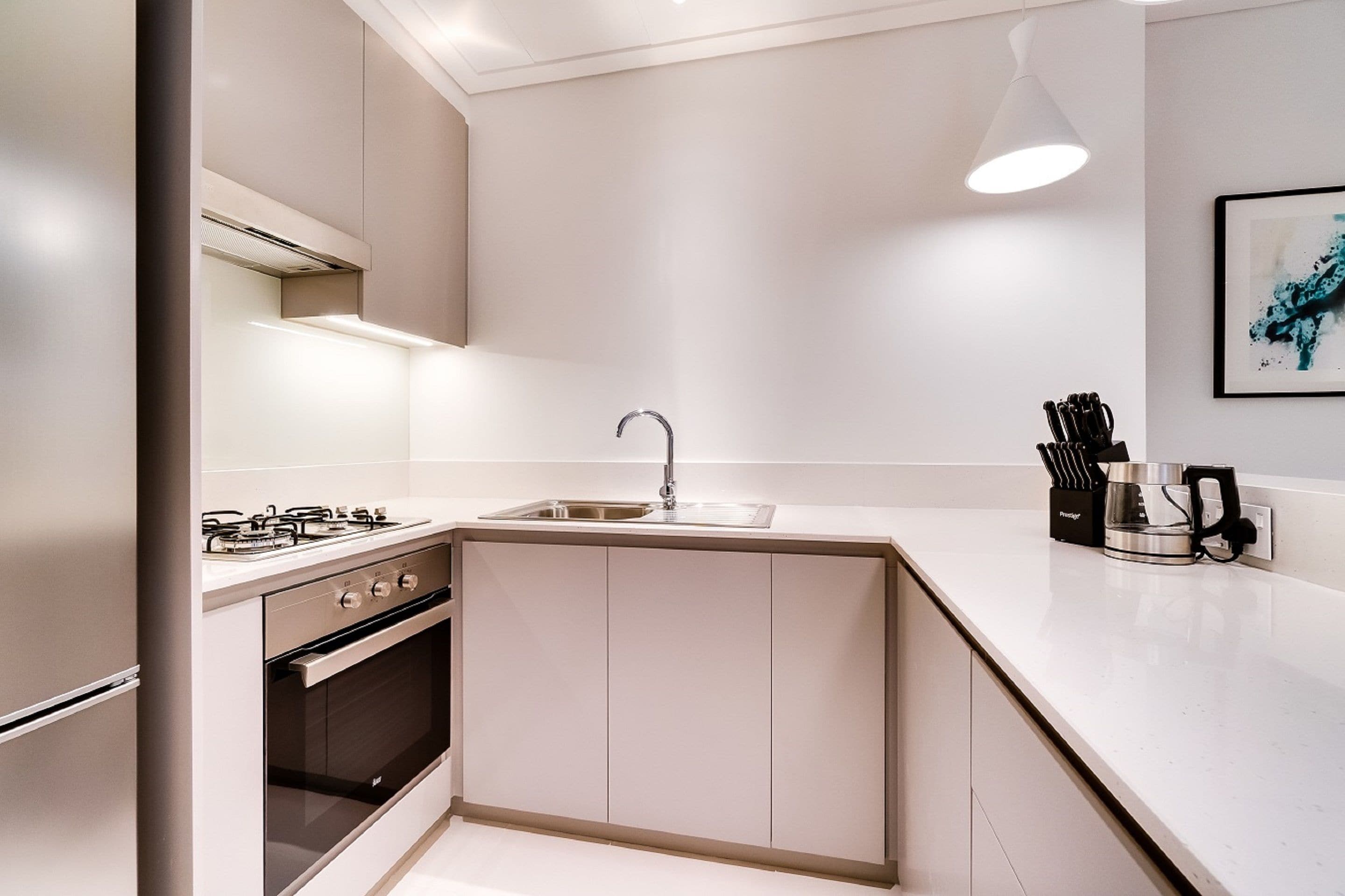 Una cucina moderna con piano cottura a gas, forno, lavello e macchina da caffè sul ripiano.