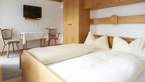 A hotel room with two beds, a TV, a desk, and chairs. - Hotel Peter (Saalbach-Hinterglemm)