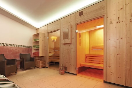 A sauna room with wooden walls, a bench, and a small table with a basket.