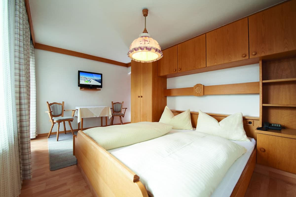 A bedroom with a bed, a television, a desk, and a chair.