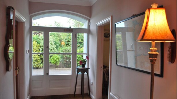 A hallway with a large arched window, a standing lamp, and a framed map on the wall. - Seapoint House (Westport)
