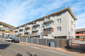 A multi-story residential building with balconies, a gated entrance, and a parked car. - Bendennis 302 (Cape Town)