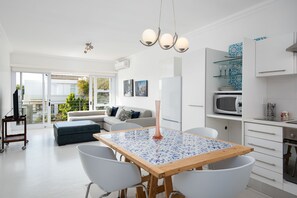 Una cucina moderna con un tavolo da pranzo, mobili bianchi e vista all'esterno.