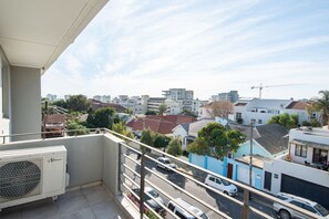 A balcony with a view of a residential street, a white car parked on the street, and a construction crane in the distance. - Bendennis 302 (Cape Town)