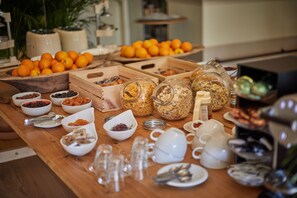 A buffet table with various food items, including fruits, nuts, and pastries, along with several cups and bowls. - Mon Boutique Hotel (Pollenca)