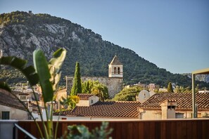 A view of a town with a prominent bell tower on a hill, surrounded by buildings with terracotta roofs. - Mon Boutique Hotel (Pollenca)