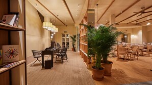 A modern hotel lobby with a reception desk, seating area, and a large potted plant. - Mon Boutique Hotel (Pollenca)