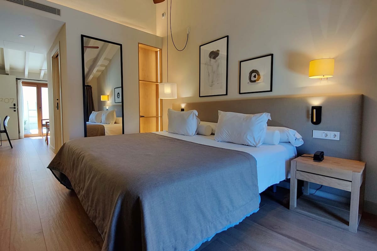 A hotel room with a large bed, bedside tables, a mirror, and wall-mounted lamps.