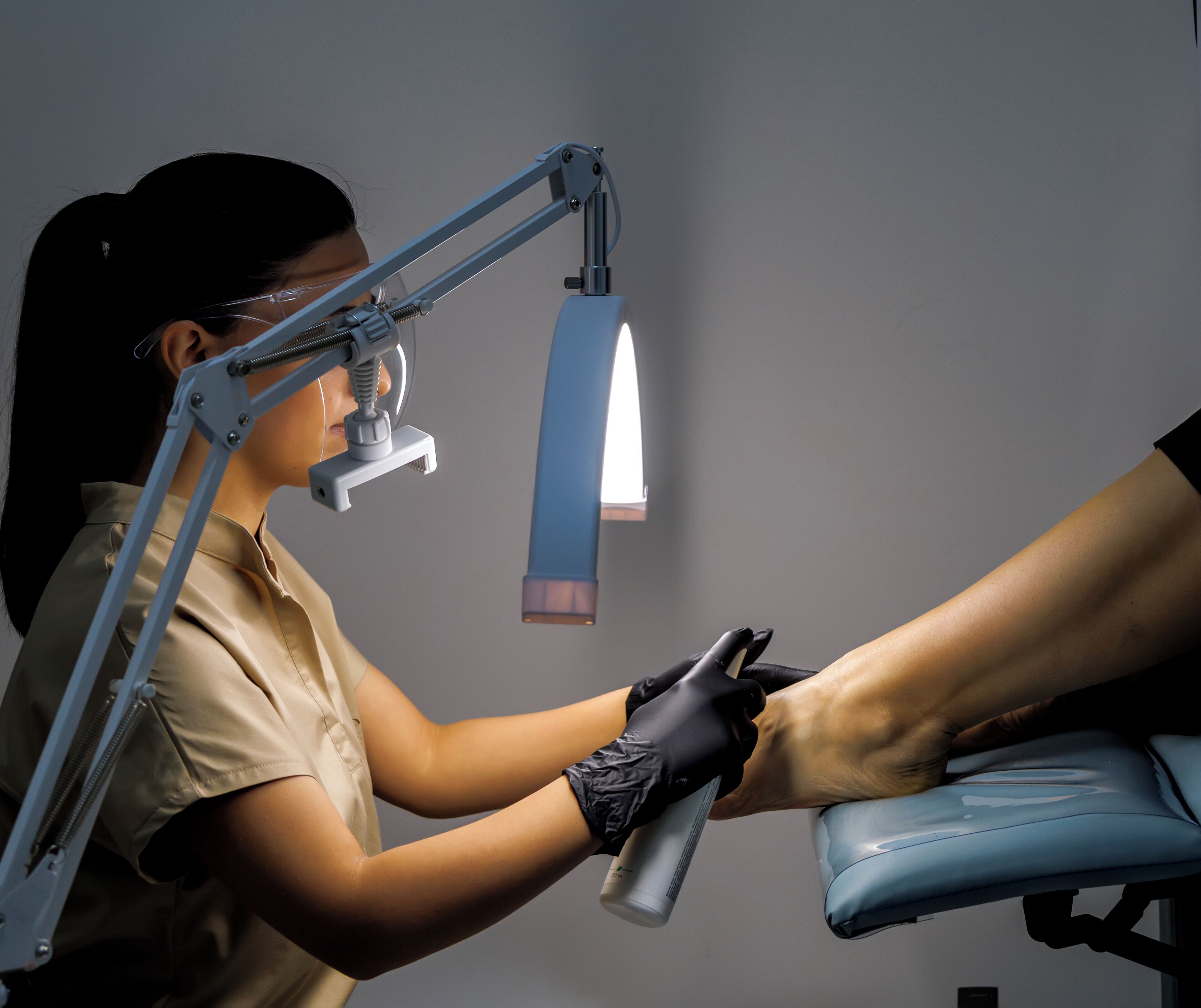 A medical professional using a lighted device on a patient's arm.