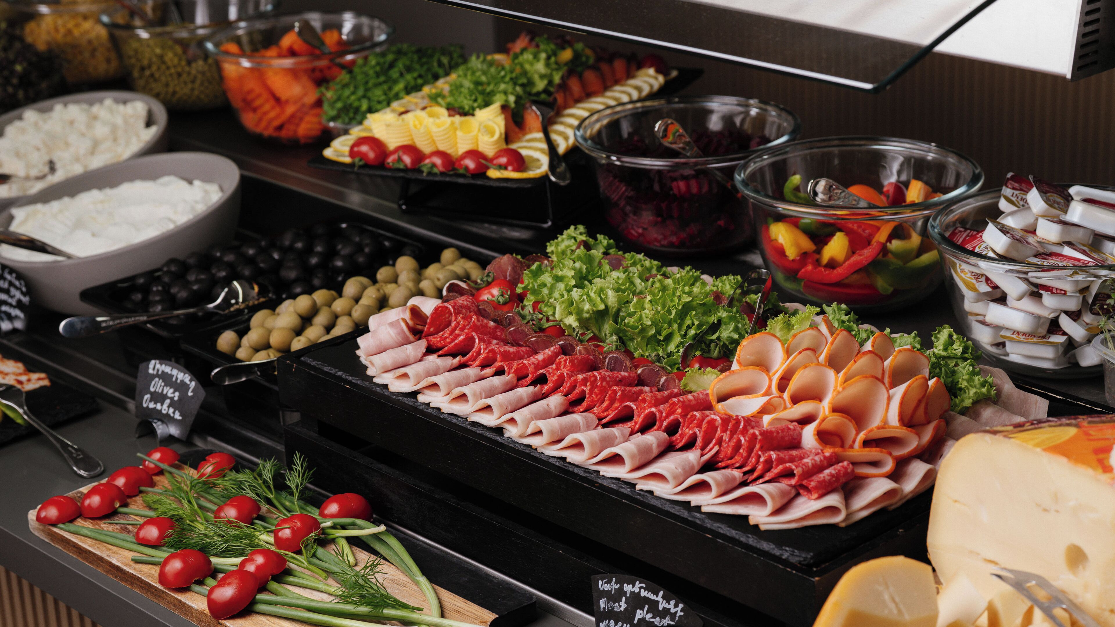 Een buffet met diverse soorten eten, zoals vleeswaren, kazen en groenten.