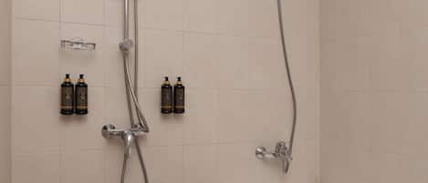 Un baño moderno con ducha, dos botellas de champú y una bañera.