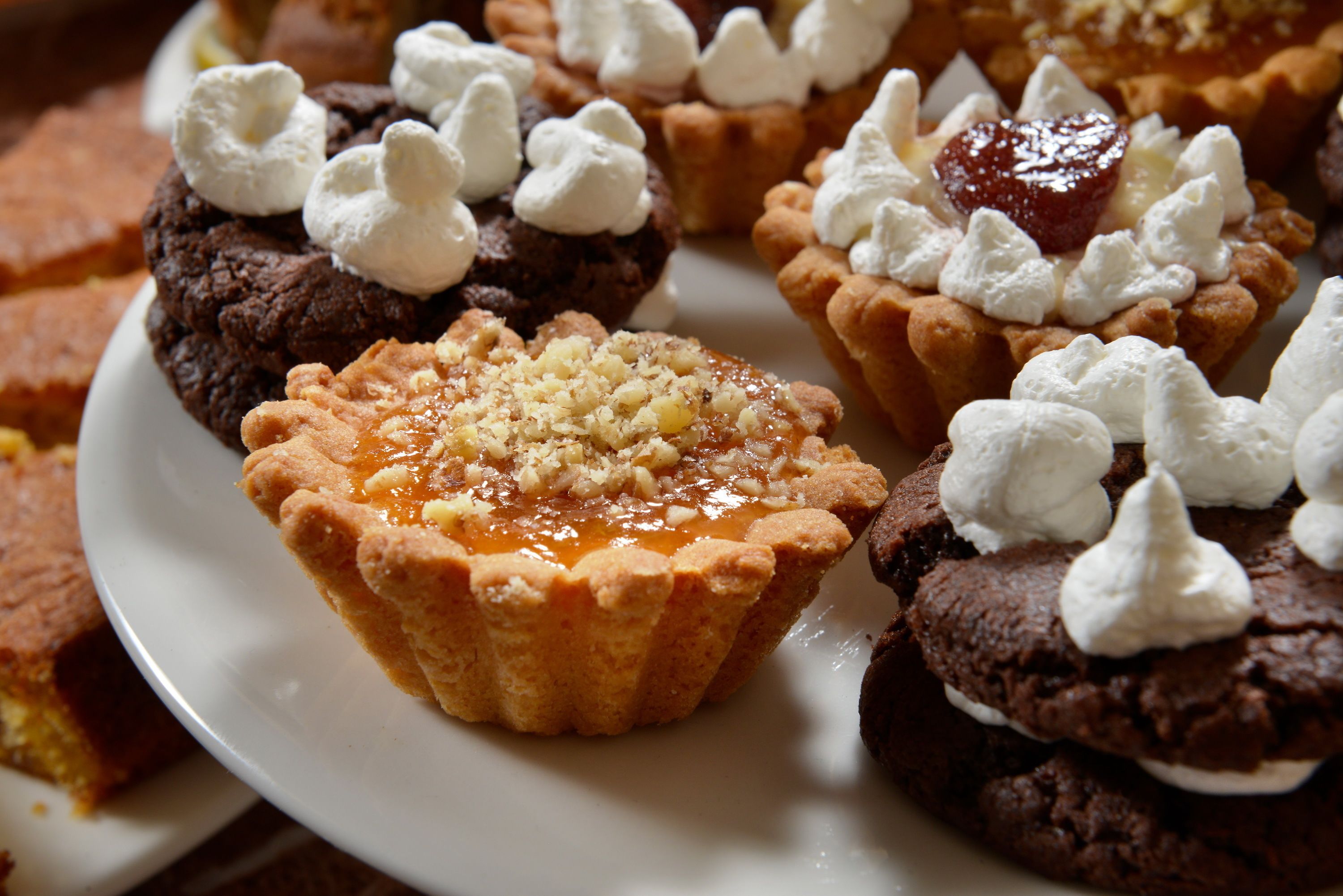 A plate of desserts including chocolate cookies and tarts with marshmallows and a fruit topping.