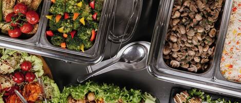 A buffet with various food options including grilled vegetables, mushrooms, and rice.