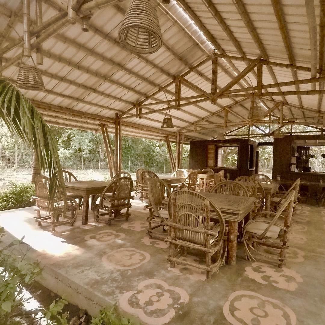 Un área de comedor al aire libre rústica, con mobiliario de bambú y una estructura simple y abierta.