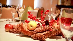 A table set with a decorative centerpiece featuring pine cones, red berries, and apples. - Hotel Spies (Gladenbach)