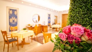 A hotel dining area with tables and chairs, a mirror, and a wall with a decorative pattern. - Hotel Spies (Gladenbach)