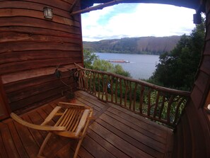 A wooden deck with a view of a lake and hills.